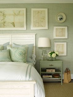 a white bed sitting in a bedroom next to a green dresser and lamp with pictures on the wall above it