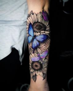 a woman's arm with a blue butterfly and sunflowers tattoo on it