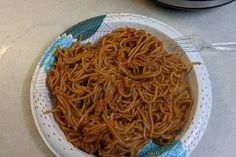 a plate full of noodles on a table next to an instant pressure cooker with the lid open