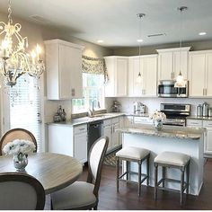 the kitchen cabinets are white and there is a table with four chairs in front of it