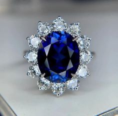 a blue and white diamond ring sitting on top of a silver tray in a display case