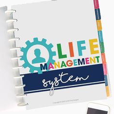 a spiral notebook with the words life management system on it next to a smart phone