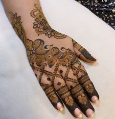 henna tattoo on the hand of a woman with brown and gold designs, which are intricately designed