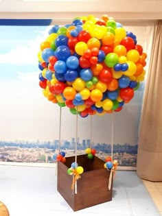 a bunch of balloons are floating in the air above a box with ribbons on it