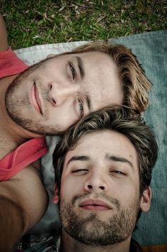 two men laying on the ground with their eyes closed and one looking at the camera