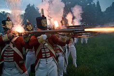 men in red and white uniforms are holding onto firecrackers as fireworks go off behind them