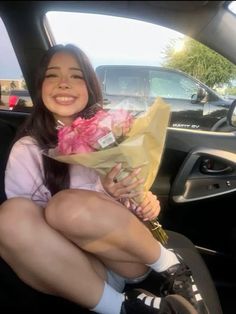 a young woman sitting in the back seat of a car holding flowers and a bouquet