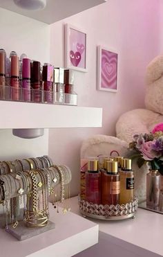 a white teddy bear sitting on top of a shelf filled with lipstick and bracelets