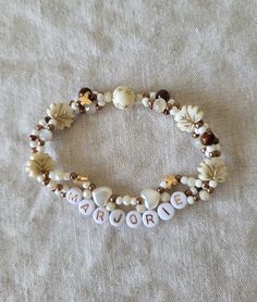 a bracelet with shells and words that spell out the word march on it, sitting on a white cloth