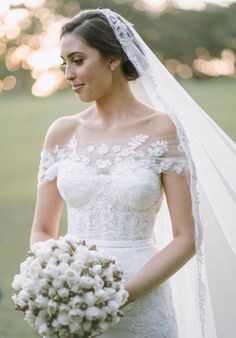 a woman in a wedding dress holding a bridal bouquet and looking off to the side