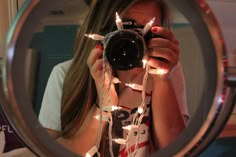 a woman taking a selfie in front of a mirror with christmas lights on it