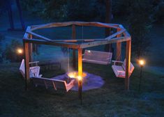 an outdoor gazebo lit up at night with candles in the foreground and benches on the other side