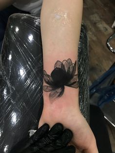 a woman's arm with a black flower tattoo on the left wrist and glove