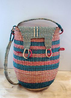 a blue and red striped bag sitting on top of a wooden table next to a white wall