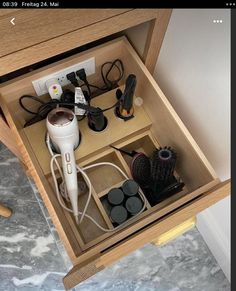 an open drawer with hairdryers and other items in it on a marble floor