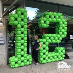 a woman standing in front of a giant letter made out of balloons