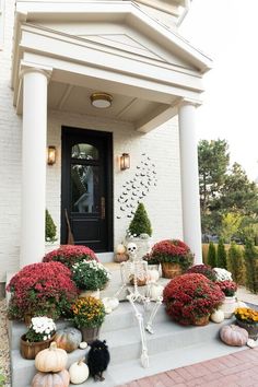 a front porch decorated for halloween with pumpkins and flowers