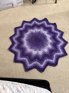 a purple crocheted doily sitting on the floor