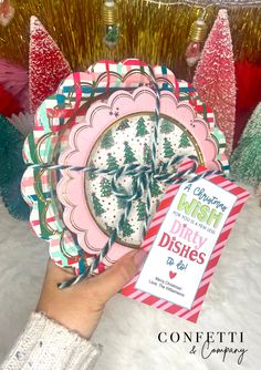 a hand holding a paper plate with trees on it and a christmas wish party wishes card