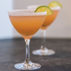 two glasses filled with drinks sitting on top of a table