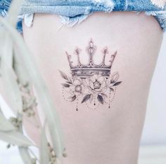 a woman's thigh with a crown tattoo on her lower leg and flowers around the thighs