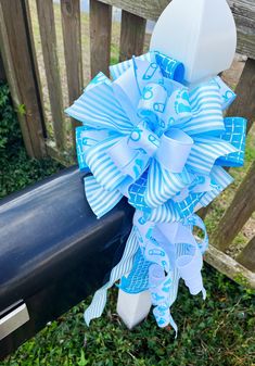 a blue and white bow on the side of a mailbox in front of a fence