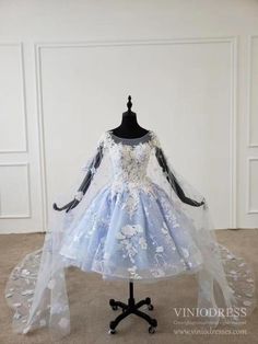 - Fairy style short prom dress with cape train - Detailing with 3D flowers and beading - Beaded bodice - Knee length dress with cathedral length cape - Built-in Bra - Back detail: Zipper Light Blue Prom Dress Poofy, Light Blue Princess Dress, Prom Dress Baby Blue, Fairytale Clothes, Quinceanera Blue, Extra Dresses, Cloud Dress, Blue Wedding Guest Dresses, Blue Princess Dress