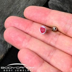 a person is holding a tiny heart shaped pin in their left hand with the word love on it