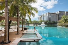 an outdoor swimming pool surrounded by palm trees