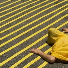 a person laying on the ground wearing a yellow raincoat and holding onto a bag