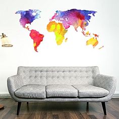 a couch sitting in front of a wall with watercolor world map painted on it