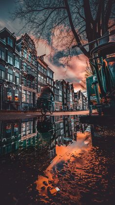 a reflection of buildings in the water at sunset