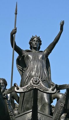 a statue of a woman holding a spear on top of a building