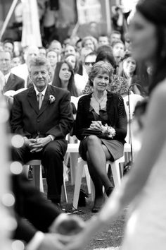 a group of people sitting next to each other in front of a crowd at a wedding