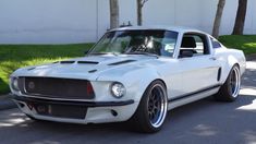 a white mustang is parked on the side of the road