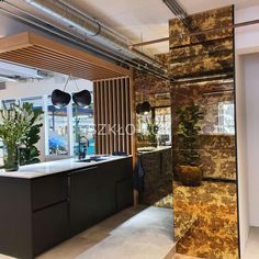 a kitchen with marble counter tops and black cabinets in an office space that is well lit