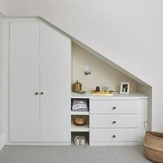 an attic bedroom with white cabinets and drawers