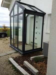 a small glass house sitting on the side of a building