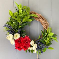 a wreath with red, white and blue flowers hanging on the wall next to a door