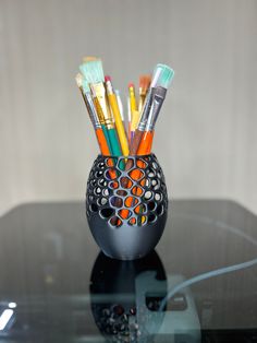 a black vase filled with lots of colorful pens and pencils on top of a table