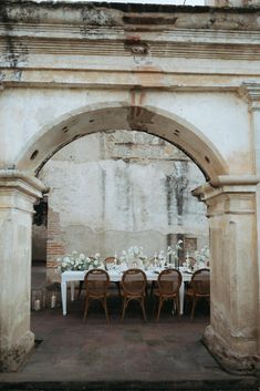 a table set up under an archway with flowers on it