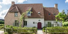 a brick house with a red door surrounded by greenery