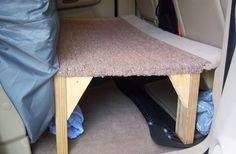 the back seat of a car with a carpeted floor and wooden table in it