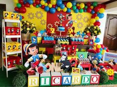 a birthday party with mickey mouse decorations and balloons on the wall, including an assortment of toys