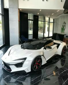 a white sports car is parked in a large room with black marble floors and walls