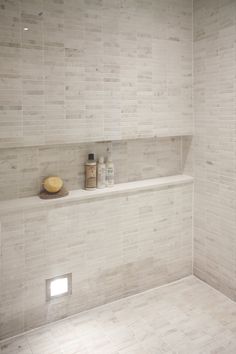 a white tiled bathroom with shelves on the wall