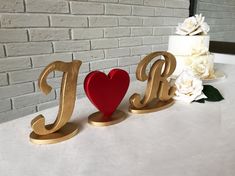 two wooden letters that spell out the word love on a table next to a cake