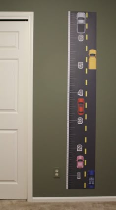 a room with a large growth chart on the wall and cars painted on the wall