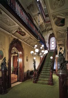 an ornately decorated entryway with chandelier and green carpet