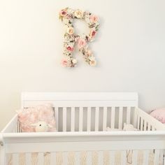 a white crib with flowers on the wall above it and a stuffed teddy bear